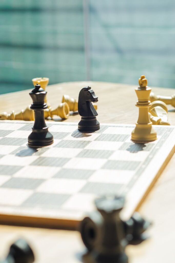 Close-up of chess pieces on a board under sunlight, highlighting strategy and focus.